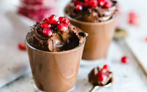 Mousse al cioccolato per profiterol, guarnita con chicchi di melagrana succosi. Un dessert goloso e invitante.