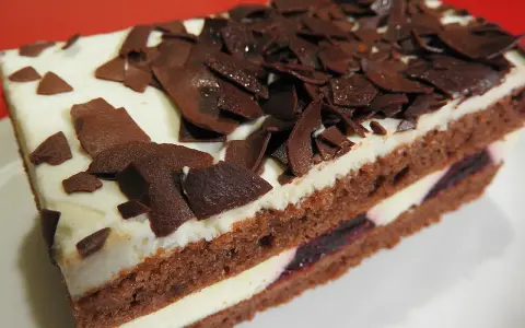Una fetta di torta foresta nera di Montersino, con pan di Spagna al cacao, panna montata e ciliegie, decorata con riccioli di cioccolato.