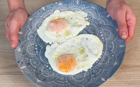 Due frittelle di uova, cotte alla perfezione, servite su un piatto blu decorato. Un classico per iniziare la giornata.