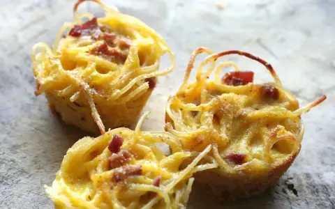 Tre tortini di pasta fritta senza glutine, dorati e croccanti, con pezzetti di pancetta.