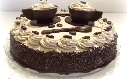 Torta decorata con ciuffi di crema al caffè, chicchi di cioccolato e due tazzine di cioccolato riempite di crema. Un vero capolavoro per gli amanti del bagna al caffè.