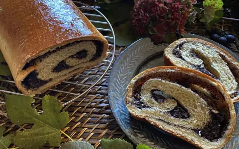 Makowiec japoński, un rotolo di pane dolce con ripieno di semi di papavero, tagliato a fette su un piatto decorato.