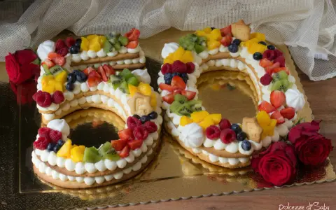 Torta 50 anni con panna, frutta fresca e biscotti a forma di numero. Un dolce colorato e delizioso per festeggiare un traguardo importante.