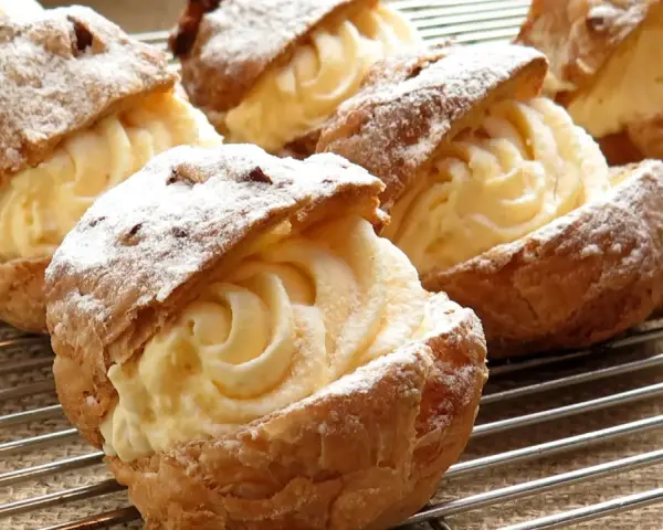 Bignè ripieni di crema pasticcera, spolverati di zucchero a velo. La farina per bignè W è perfetta per questa preparazione.
