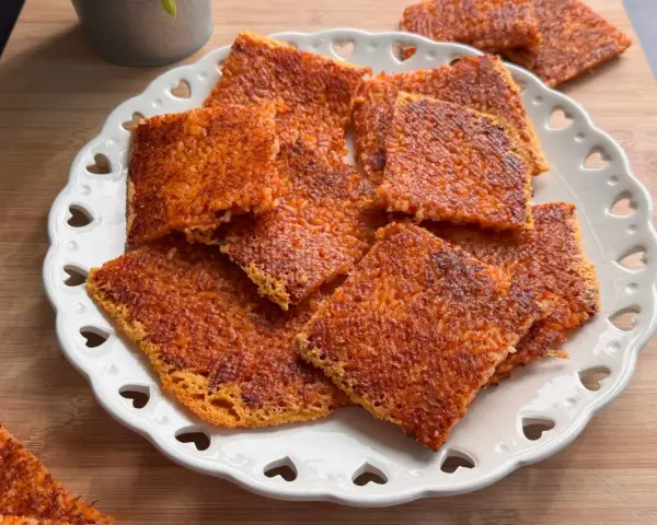 Schiacciata di riso croccante, dorata e invitante, servita su un piatto bianco decorato con cuoricini. Perfetta per uno snack goloso.