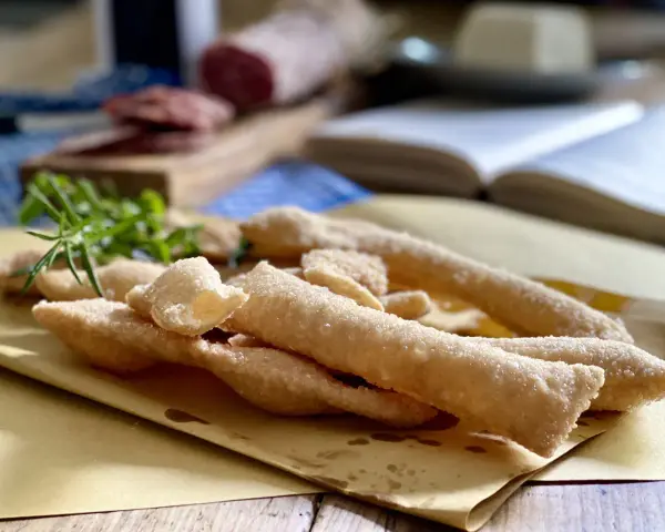 Sgabei fritti dorati e croccanti, profumati con rosmarino fresco, pronti per essere gustati con salumi e formaggio.