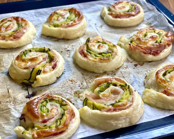 Rotolini dorati di pasta sfoglia con zucchine e scamorza filante, appena sfornati e pronti per essere gustati.