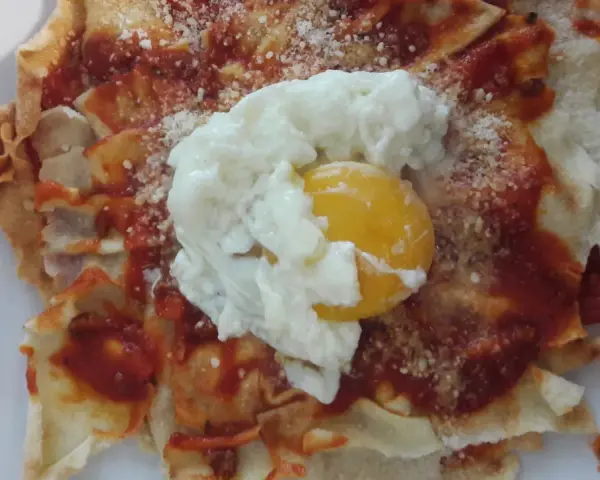 Spianata sarda come farcirla: croccante base con sugo rosso, formaggio grattugiato e un uovo in camicia.