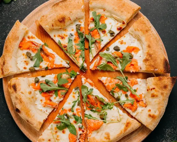 Fette di pizza con salmone affumicato, rucola e capperi, perfette come pizza sticks per un aperitivo.