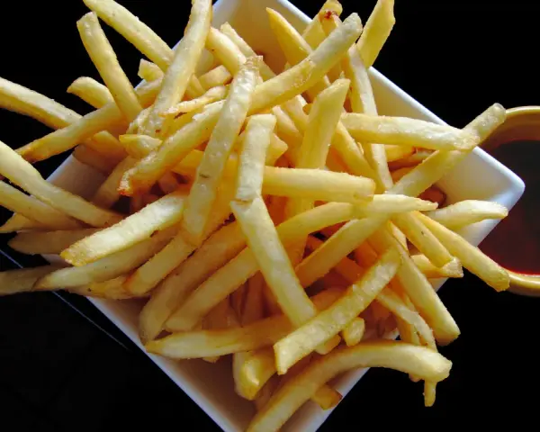 Un piatto di croccanti patatine fritte, perfette per un aperitivo, con una ciotolina di salsa rossa. Un classico intramontabile, come i veri frytki po włosku.