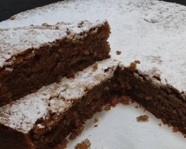 Una fetta di torta di noci della nonna, soffice e cosparsa di zucchero a velo, invita a un assaggio di tradizione.
