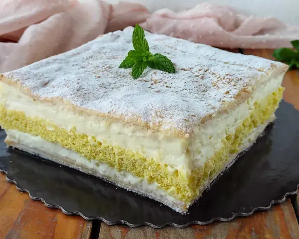 Una deliziosa torta di compleanno con pasta sfoglia e pan di spagna, farcita con crema e decorata con zucchero a velo e menta.