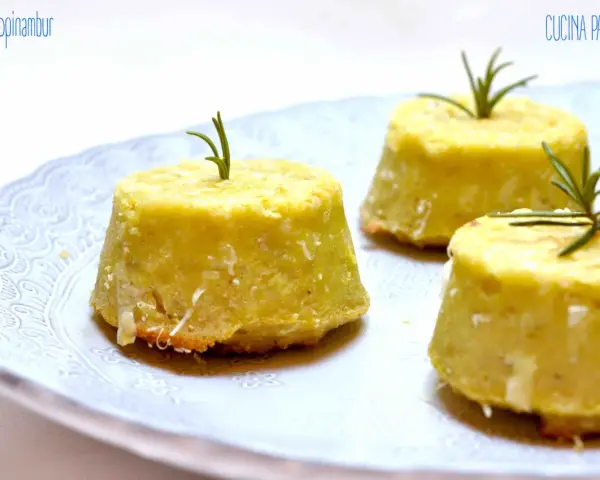 Flan di topinambur senza patate, dorati e profumati, guarniti con rosmarino fresco su un piatto bianco decorato.