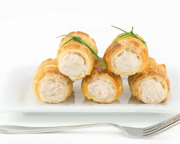 Cannoli salati ripieni di tonno, guarniti con erba cipollina, su un piatto bianco con forchetta.