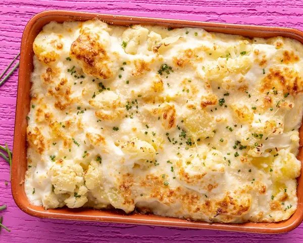Sformato di cavolfiore e ricotta dorato e filante, guarnito con erba cipollina, pronto per essere gustato.