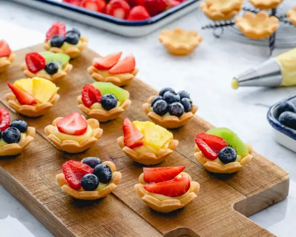 Deliziosi cestini di frutta ricetta, preparati con fragole, mirtilli, kiwi e ananas su una base di crema.