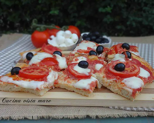 Fette di pizza saporita con pomodoro fresco, mozzarella filante e olive nere. Ingredienti semplici per un gusto autentico.