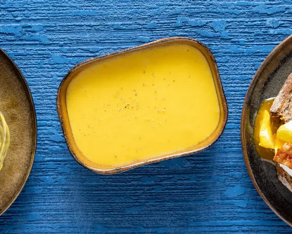Salsa olandese, perfetta per la tua sfoglia olandese ricetta. Accanto, un uovo in camicia su pane tostato.