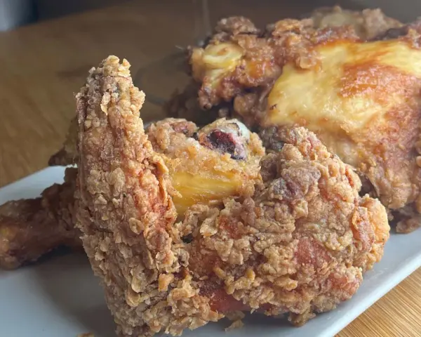 Pollo fritto croccante, un chrusty przepis che fa venire l'acquolina in bocca. Pezzi dorati e succulenti su un piatto bianco.
