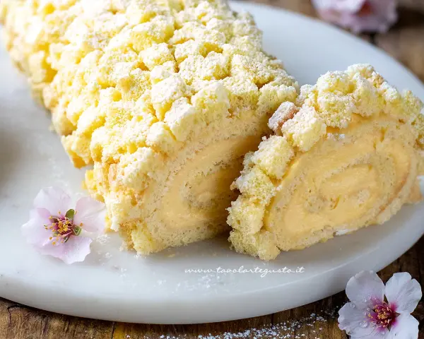 Tronchetto mimosa soffice e cremoso, decorato con briciole di pan di Spagna e fiori rosa.