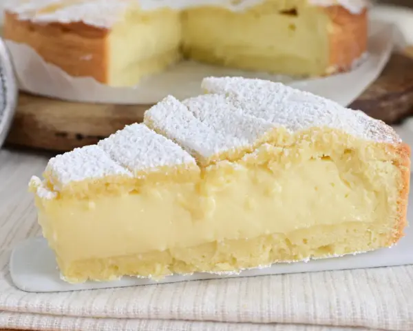 Fetta di crostata con abbondante crema allo yogurt, cosparsa di zucchero a velo.
