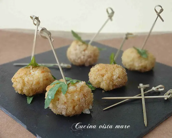 Deliziose polpette finger food con salsa, servite su una pietra scura, pronte per essere gustate.