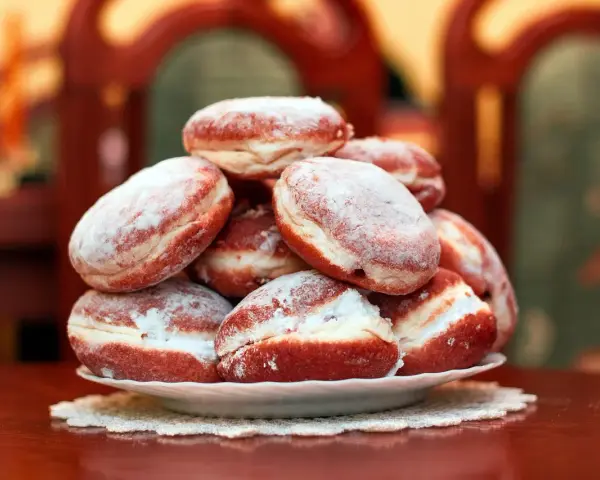 Pila di bomboloni zuccherati, pronti per il tłusty czwartek. Deliziosi dolcetti che invitano a festeggiare.