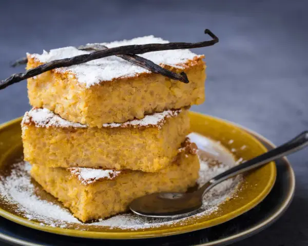 Tre fette impilate di torta di riso fiorentina, spolverate di zucchero a velo e decorate con baccelli di vaniglia.