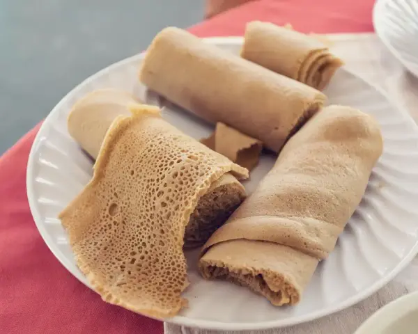 Piadina africana, un piatto di injera arrotolata, con la sua tipica trama alveolata, pronta per essere gustata.