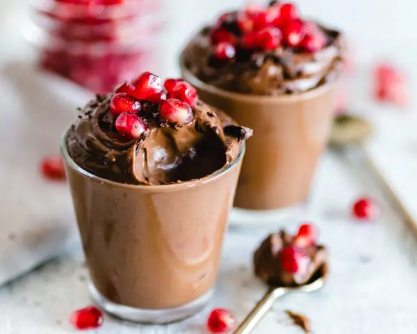 Mousse al cioccolato per profiterol, guarnita con chicchi di melagrana succosi. Un dessert goloso e invitante.