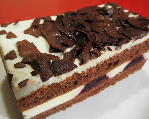 Una fetta di torta foresta nera di Montersino, con pan di Spagna al cacao, panna montata e ciliegie, decorata con riccioli di cioccolato.