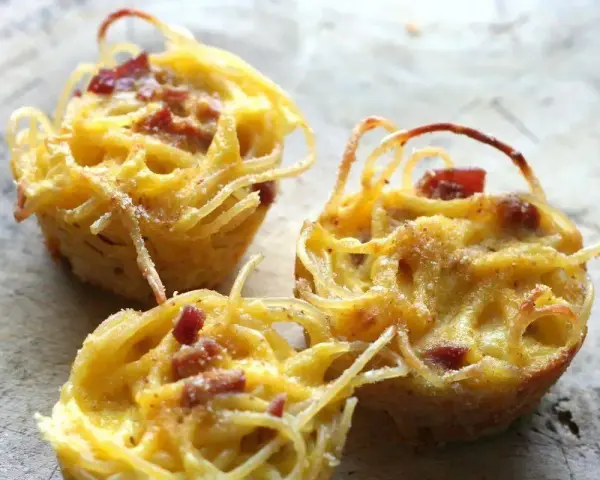 Tre tortini di pasta fritta senza glutine, dorati e croccanti, con pezzetti di pancetta.