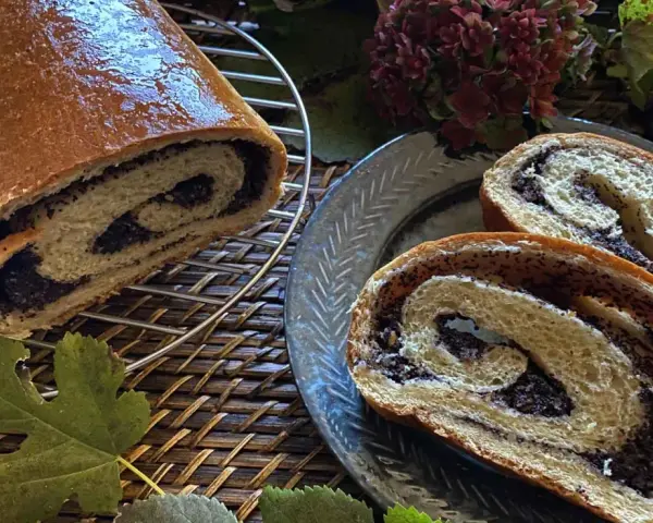 Makowiec japoński, un rotolo di pane dolce con ripieno di semi di papavero, tagliato a fette su un piatto decorato.