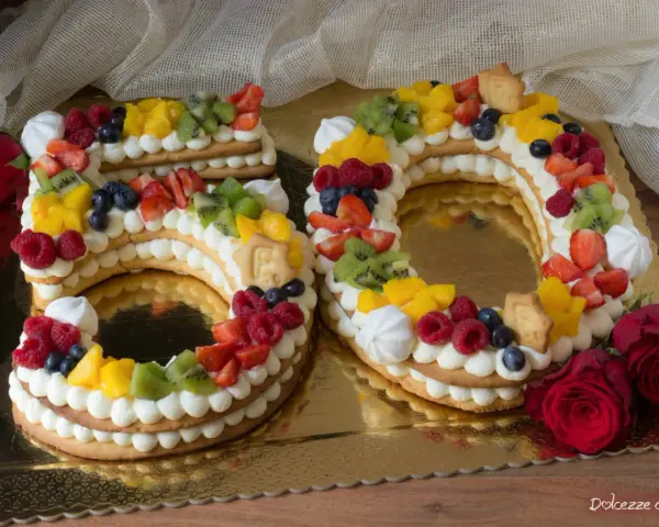 Torta 50 anni con panna, frutta fresca e biscotti a forma di numero. Un dolce colorato e delizioso per festeggiare un traguardo importante.