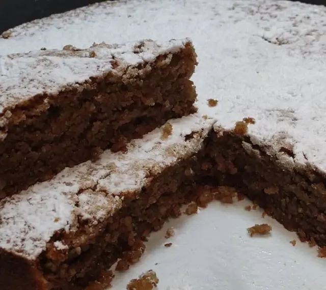 Una fetta di torta di noci della nonna, soffice e cosparsa di zucchero a velo, invita a un assaggio di tradizione.