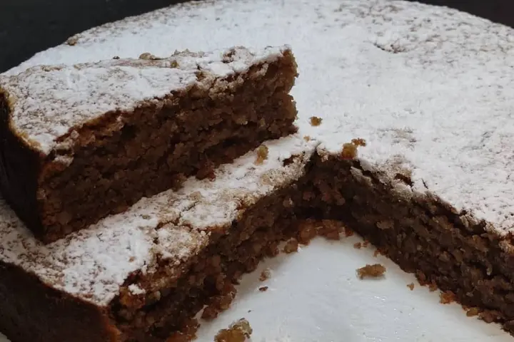 Una fetta di torta di noci della nonna, soffice e cosparsa di zucchero a velo, invita a un assaggio di tradizione.