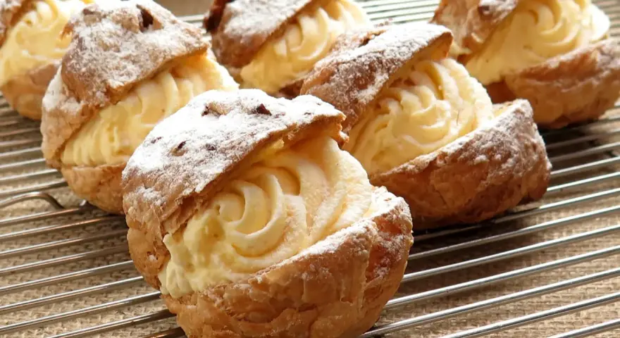 Bignè ripieni di crema pasticcera, spolverati di zucchero a velo. La farina per bignè W è perfetta per questa preparazione.