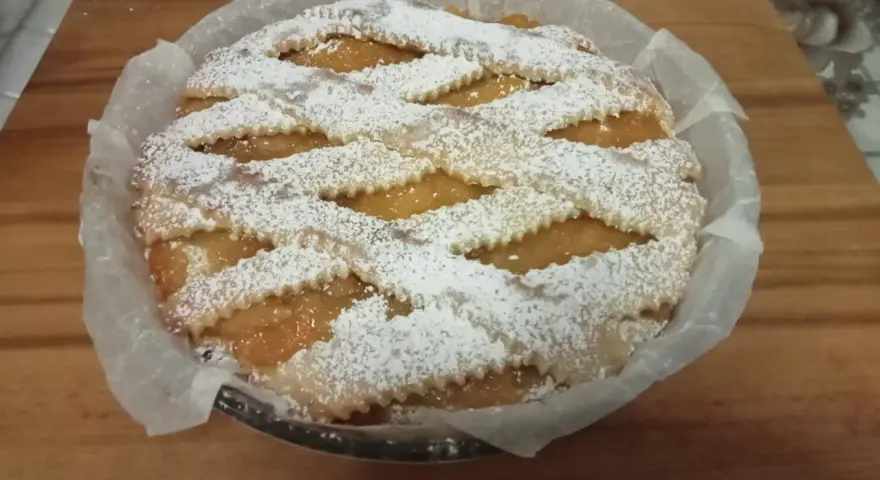 Una deliziosa crostata pasqualina salata, con un intreccio di pasta frolla cosparso di zucchero a velo, pronta per essere gustata.