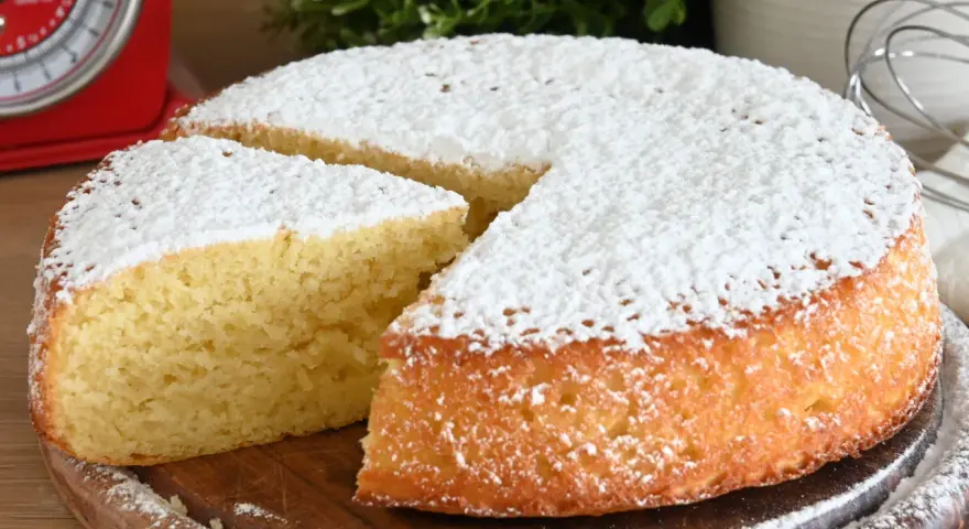 Delizioso ciasto jogurtowe, soffice e cosparso di zucchero a velo, pronto per essere gustato.
