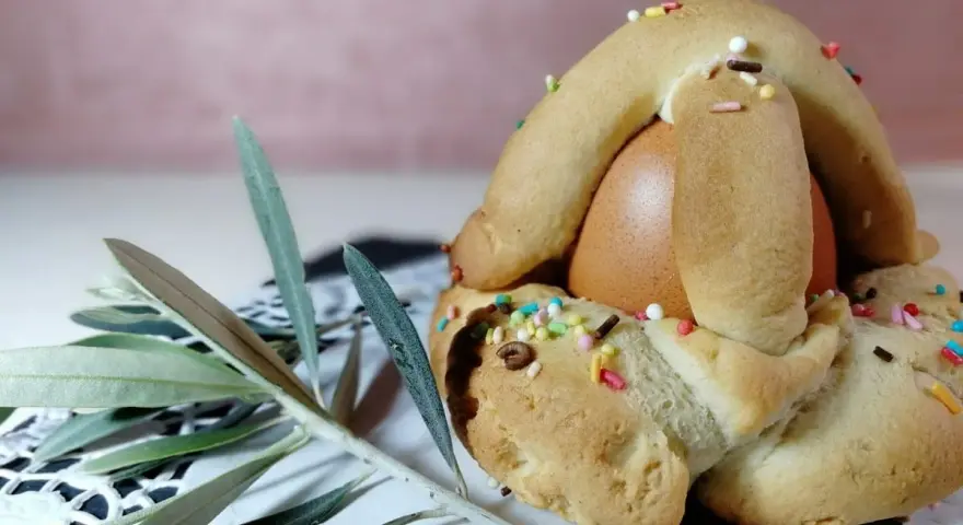 Dolci biscotti con uovo sodo, decorati con zuccherini colorati, pronti per essere gustati. Un ramoscello d'ulivo completa la scena.
