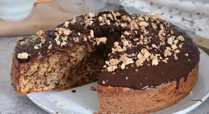 Torta soffice con amaretti e cioccolato fondente, glassata al cioccolato e cosparsa di briciole croccanti.