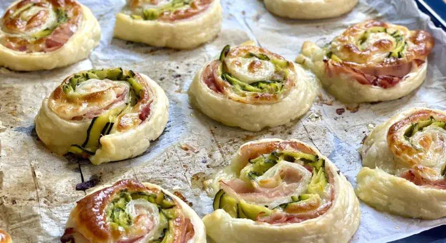 Rotolini dorati di pasta sfoglia con zucchine e scamorza filante, appena sfornati e pronti per essere gustati.