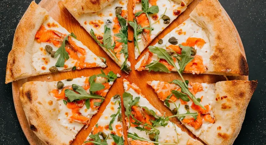 Fette di pizza con salmone affumicato, rucola e capperi, perfette come pizza sticks per un aperitivo.
