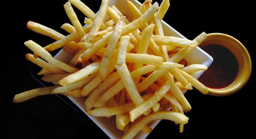 Un piatto di croccanti patatine fritte, perfette per un aperitivo, con una ciotolina di salsa rossa. Un classico intramontabile, come i veri frytki po włosku.