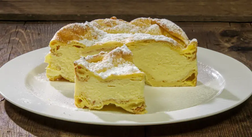 Fetta di Karpatka, dolce polacco con crema pasticcera e pasta choux, spolverata di zucchero a velo. Un delizioso karpatka przepis.