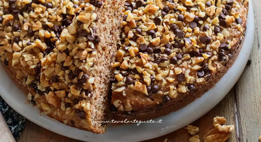 Torta noci e amaretti, soffice e golosa, ricoperta di noci tritate e gocce di cioccolato.