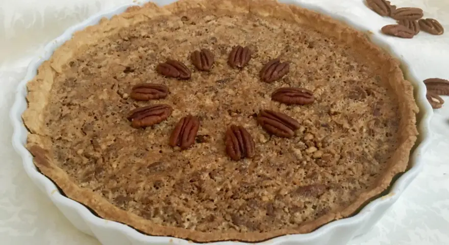 Torta di noci croccante e dorata, decorata con noci intere disposte a cerchio. Un delizioso pandi noci pronto da gustare.