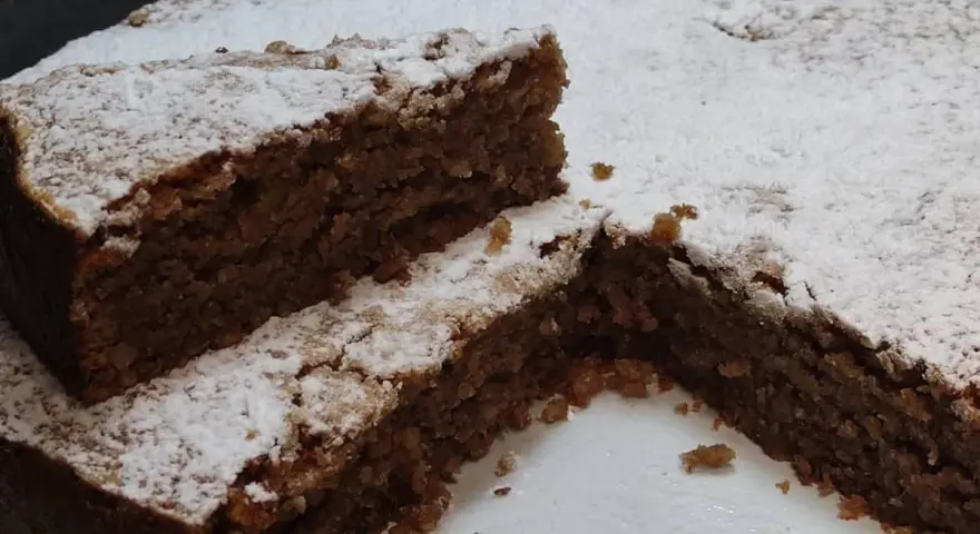 Una fetta di torta di noci della nonna, soffice e cosparsa di zucchero a velo, invita a un assaggio di tradizione.