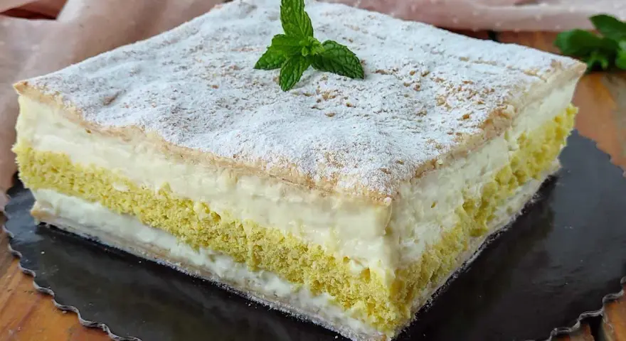 Una deliziosa torta di compleanno con pasta sfoglia e pan di spagna, farcita con crema e decorata con zucchero a velo e menta.