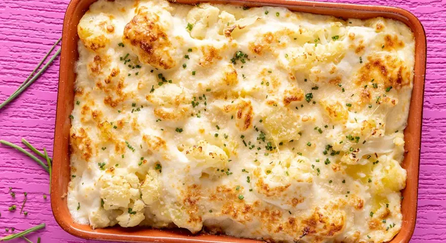 Sformato di cavolfiore e ricotta dorato e filante, guarnito con erba cipollina, pronto per essere gustato.